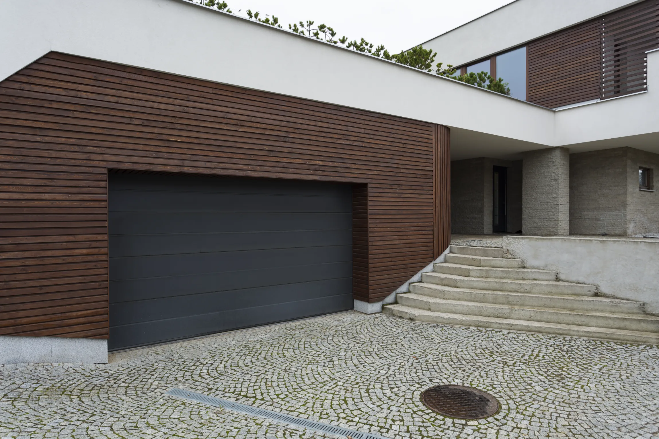 Steel garage door installation on a modern home exterior.